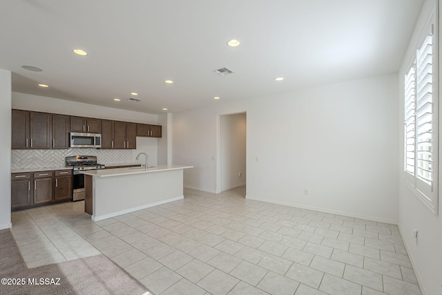 kitchen featuring tasteful backsplash, visible vents, open floor plan, stainless steel appliances, and light countertops