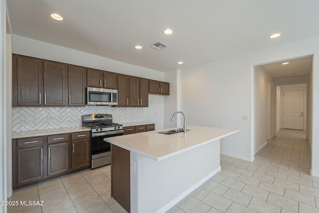 kitchen with tasteful backsplash, light countertops, appliances with stainless steel finishes, a sink, and dark brown cabinets