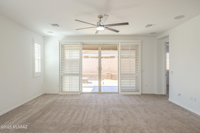 carpeted spare room featuring ceiling fan, visible vents, and baseboards