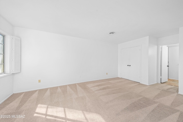 spare room featuring light carpet and visible vents