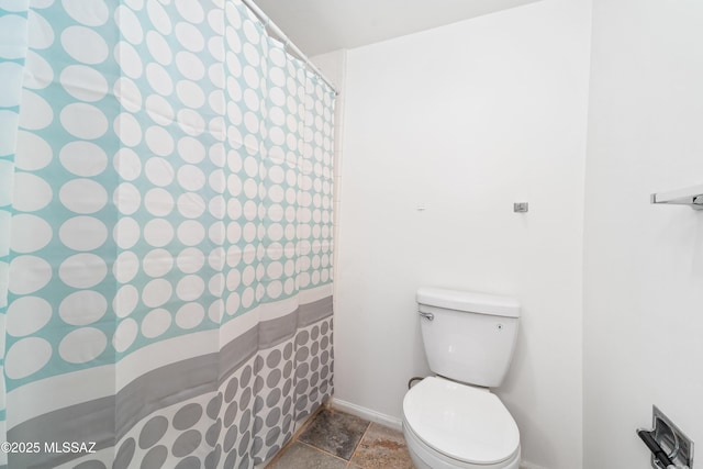 full bath with toilet, baseboards, and stone finish floor