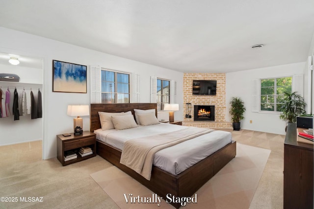 bedroom featuring light carpet, a brick fireplace, and visible vents