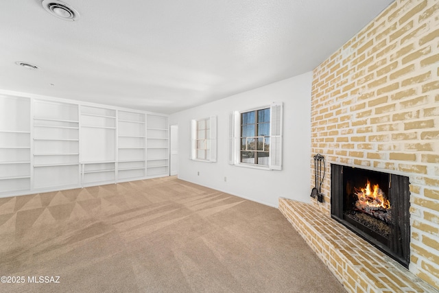 unfurnished living room featuring light carpet, a brick fireplace, visible vents, and a textured ceiling