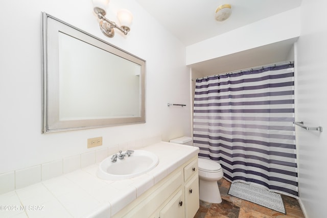 bathroom featuring stone finish floor, vanity, and toilet