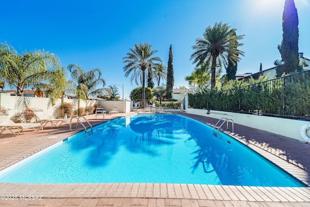 community pool with a patio area and fence