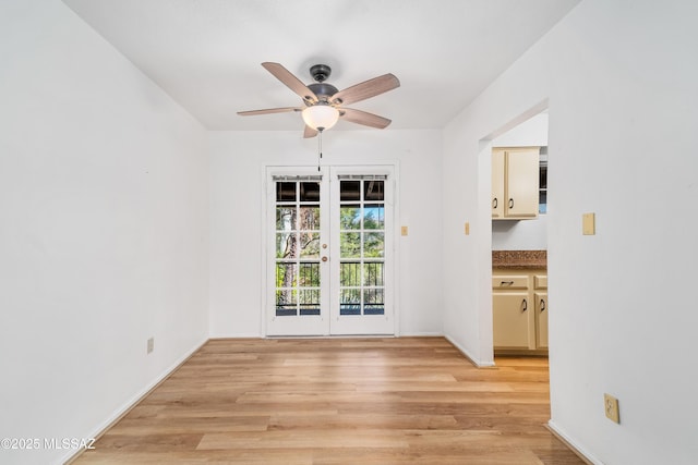 empty room with light wood-type flooring, baseboards, a ceiling fan, and french doors