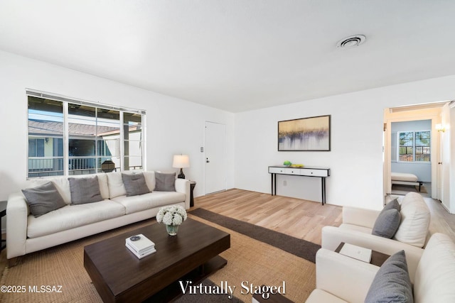 living area with visible vents and wood finished floors