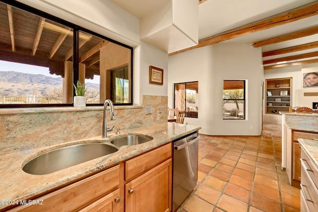 kitchen with light stone counters, a sink, a mountain view, and dishwasher