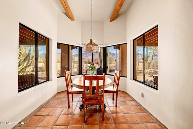 tiled dining room with beamed ceiling and a towering ceiling