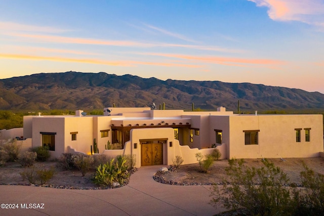 southwest-style home featuring a mountain view, driveway, and stucco siding