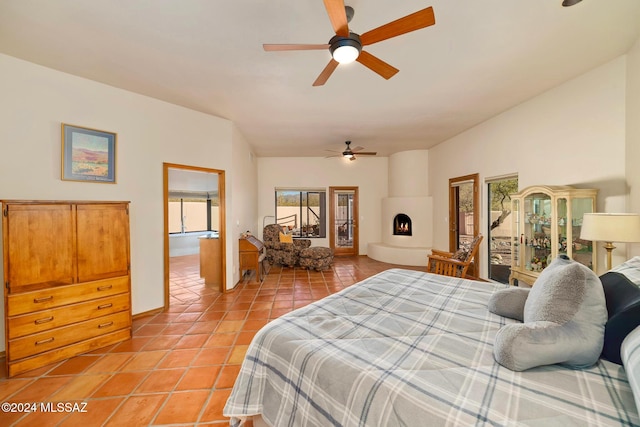 bedroom featuring light tile patterned floors, lofted ceiling, ceiling fan, access to exterior, and a fireplace