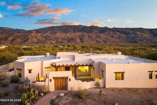 pueblo revival-style home with a chimney, a mountain view, and stucco siding