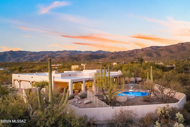 pool at dusk with a mountain view and fence