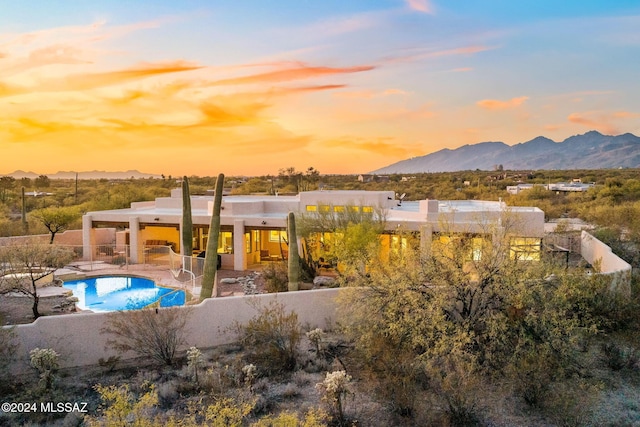 rear view of house with a patio area, a fenced backyard, a mountain view, and an outdoor pool