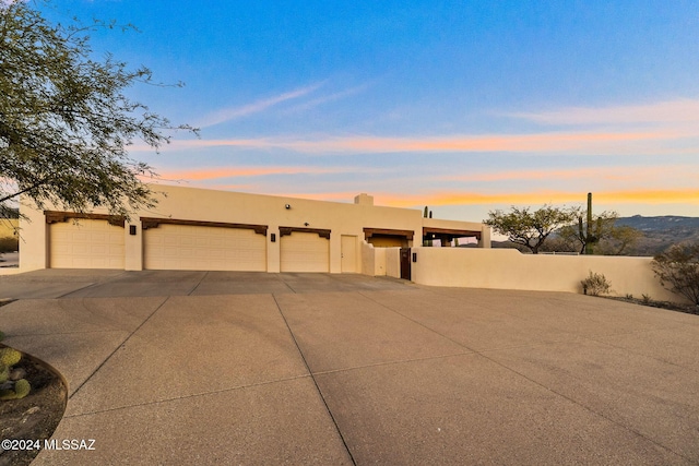 adobe home with a garage, fence, and stucco siding