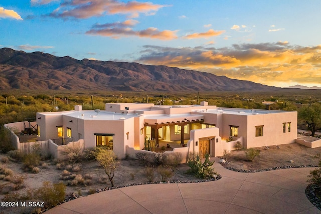 view of front of home with fence, a mountain view, a chimney, and stucco siding