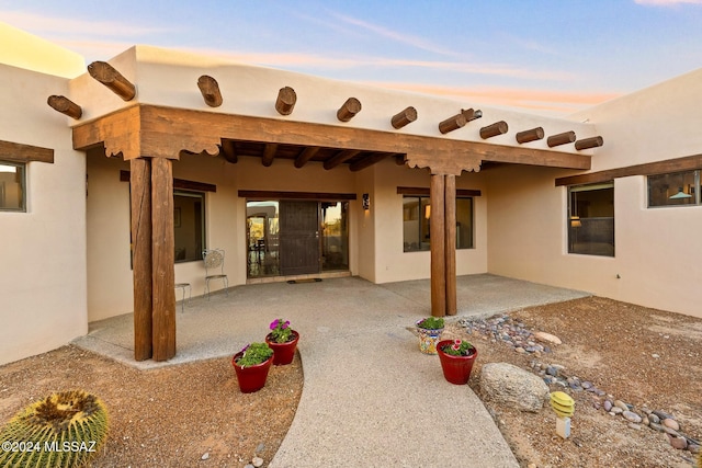 back of house at dusk featuring a patio area