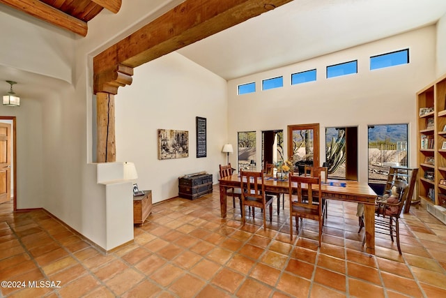 dining space with beam ceiling, a towering ceiling, baseboards, and tile patterned floors