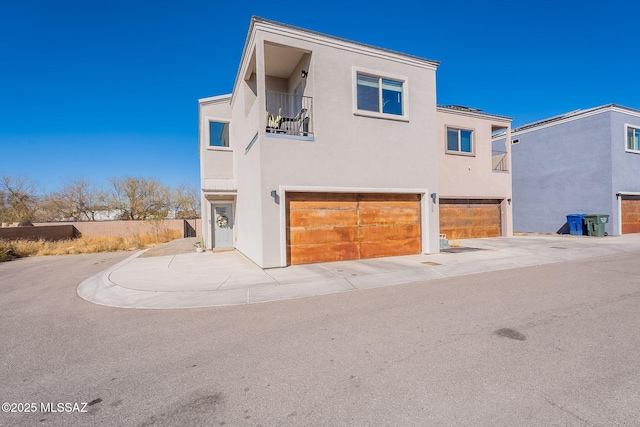 view of front facade with a balcony, an attached garage, and stucco siding