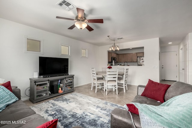 living room featuring light tile patterned floors, ceiling fan with notable chandelier, visible vents, and baseboards