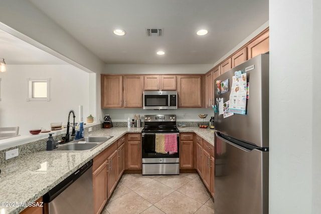 kitchen featuring light stone counters, light tile patterned floors, stainless steel appliances, visible vents, and a sink