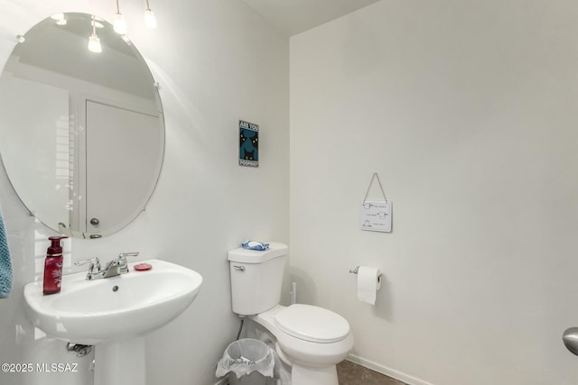 half bathroom with toilet, baseboards, and a sink