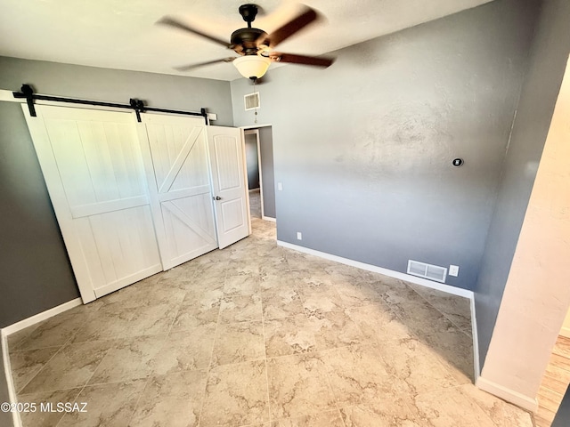 unfurnished bedroom with a barn door, visible vents, and baseboards