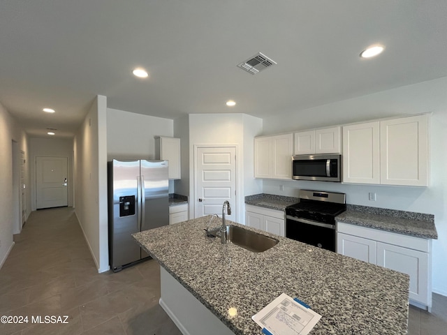 kitchen with appliances with stainless steel finishes, a kitchen island with sink, white cabinetry, and a sink