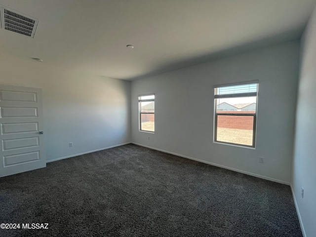 unfurnished room featuring baseboards, visible vents, and dark carpet