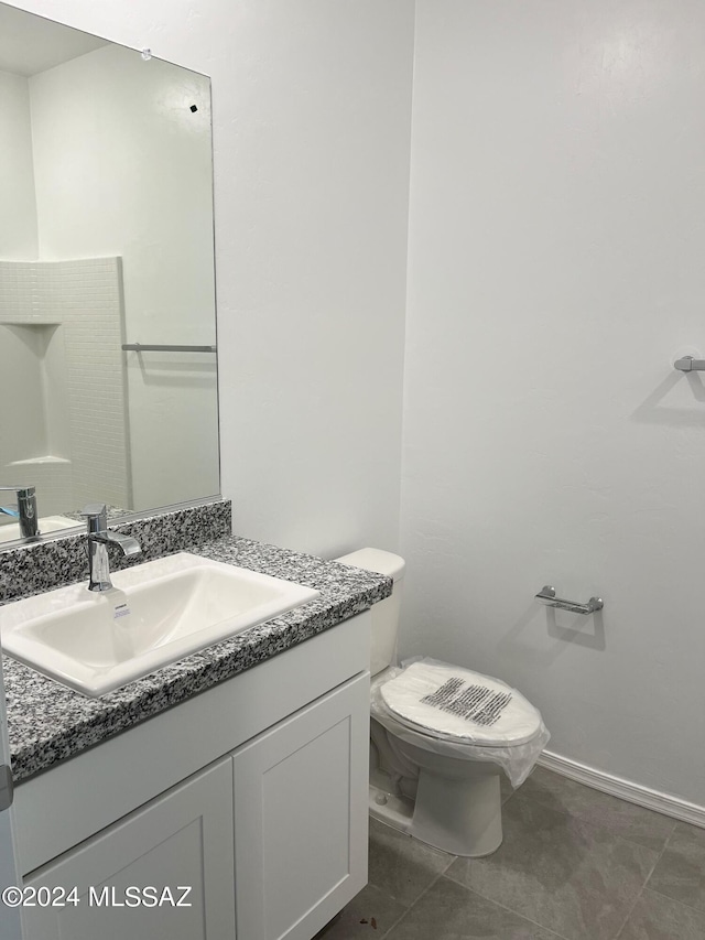 bathroom with tile patterned flooring, baseboards, vanity, and toilet