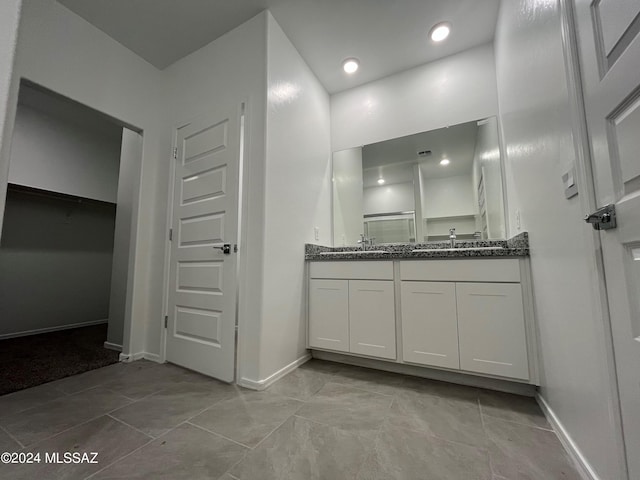 bathroom with double vanity, recessed lighting, a spacious closet, a sink, and baseboards