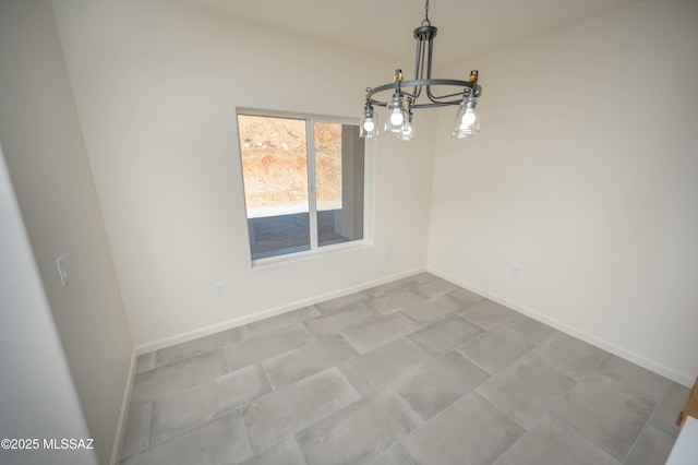 spare room with baseboards and an inviting chandelier