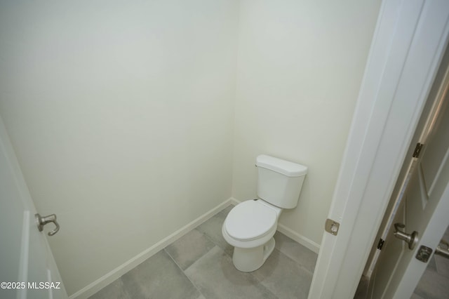 bathroom with baseboards, toilet, and tile patterned floors