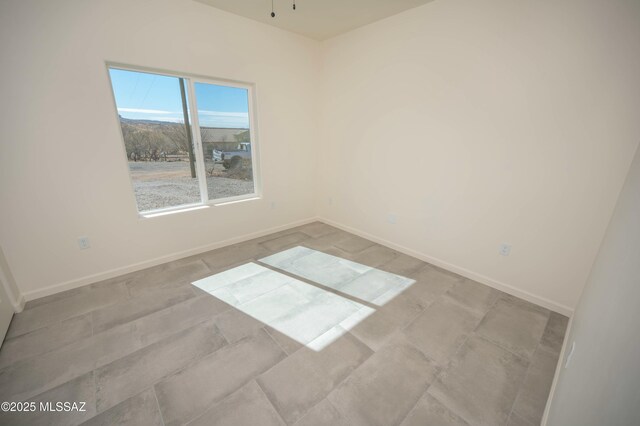 empty room with a ceiling fan and baseboards