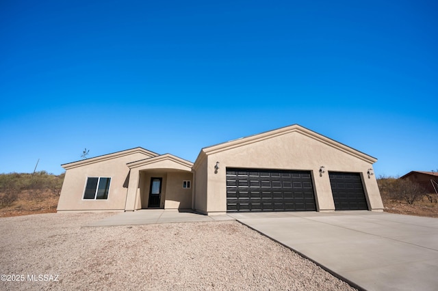 view of front of home featuring a garage, concrete driveway, and stucco siding