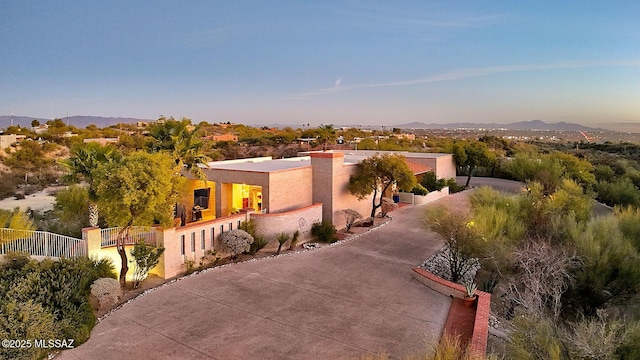 view of front of home with driveway, fence, a mountain view, and stucco siding