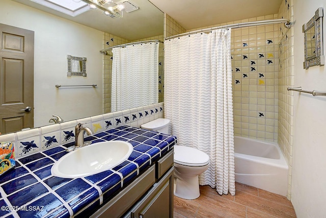 bathroom with toilet, shower / bathtub combination with curtain, wood finish floors, and vanity