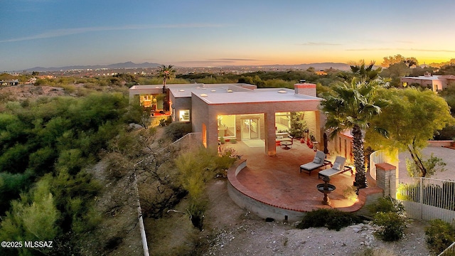 exterior space featuring a chimney, fence, a mountain view, and a patio