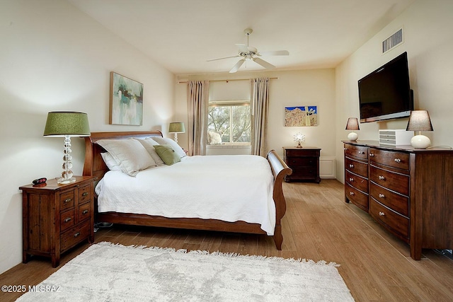 bedroom featuring light wood-style floors, visible vents, and a ceiling fan