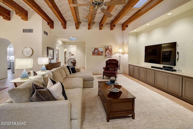 living area with visible vents, arched walkways, wooden ceiling, ceiling fan, and beam ceiling