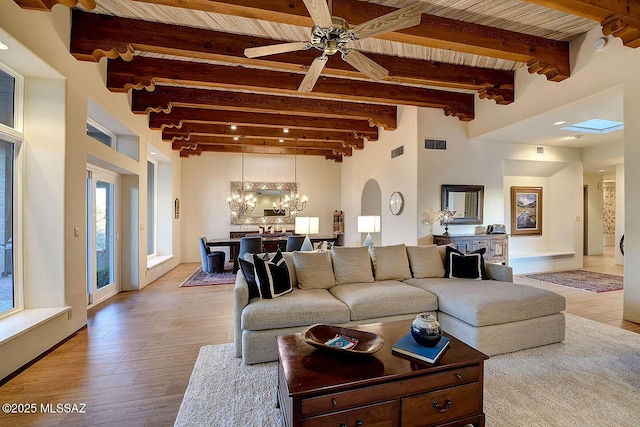 living room with light wood-style flooring, visible vents, and beam ceiling