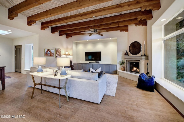 living area featuring wood ceiling, light wood-type flooring, a large fireplace, and beam ceiling