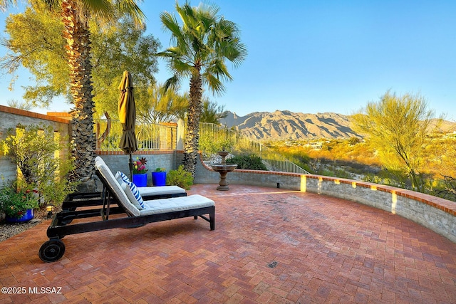 view of patio with a mountain view and fence