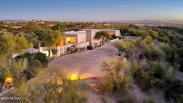 exterior space featuring driveway, a chimney, fence, a mountain view, and stucco siding