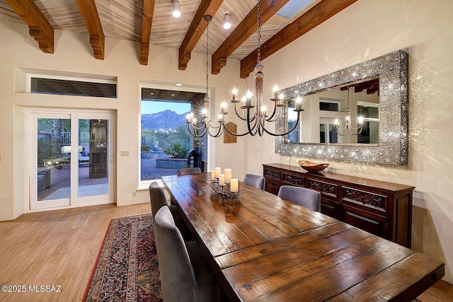 dining area with beam ceiling, light wood-style flooring, an inviting chandelier, a mountain view, and wooden ceiling