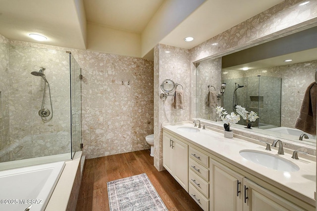 bathroom with double vanity, a sink, a shower stall, and wood finished floors