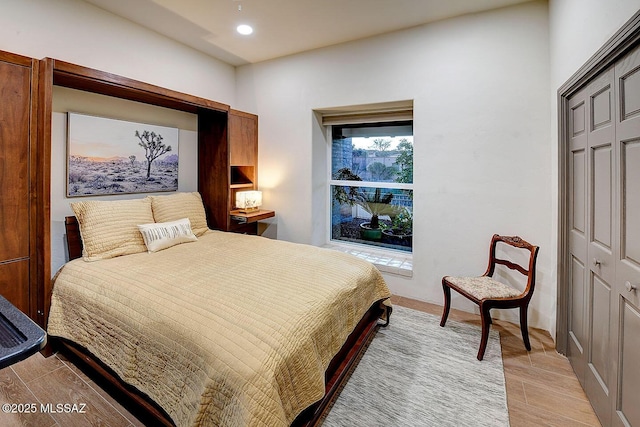 bedroom with wood finish floors, a closet, and recessed lighting