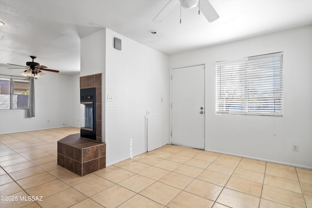 interior space with a ceiling fan, light tile patterned flooring, and a fireplace