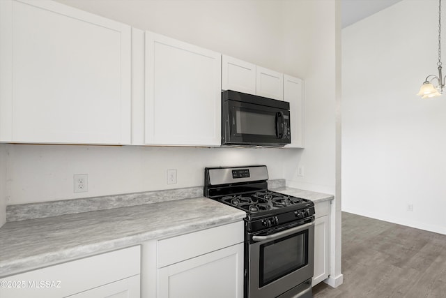 kitchen featuring stainless steel gas stove, black microwave, light countertops, and white cabinets