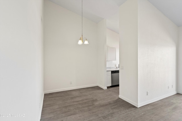 interior space with lofted ceiling, a notable chandelier, baseboards, and wood finished floors